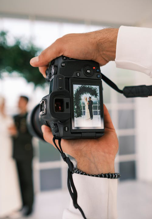 Professional wedding photographer with camera capturing a bride and groom