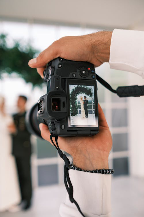 Professional wedding photographer with camera capturing a bride and groom