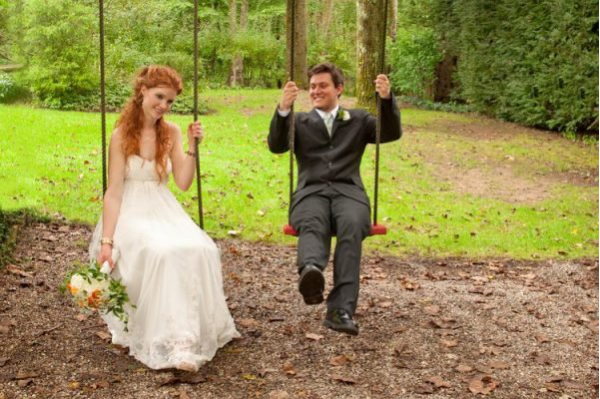 A couple sitting on a rustic swing in New Haven, Connecticut, surrounded by greenery, captured by skilled wedding videographers.